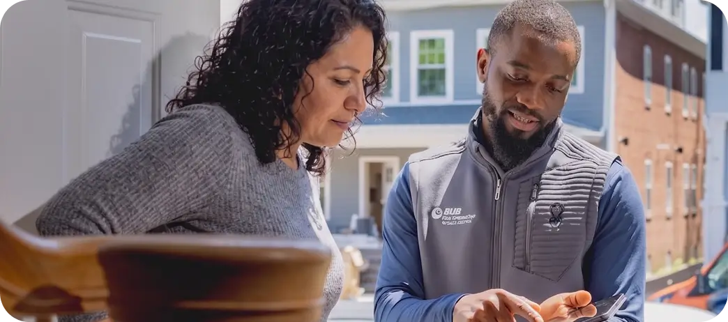 Service technician shows a woman information on a tablet outside a home