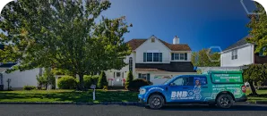 BMB service truck parked in front of a suburban home on a tree-lined street