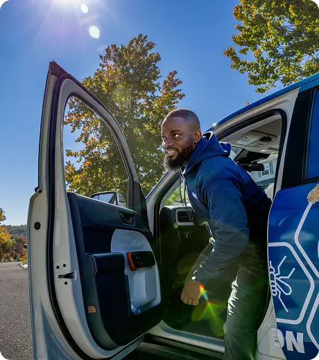 Man smiling while stepping into a branded service vehicle on a sunny day